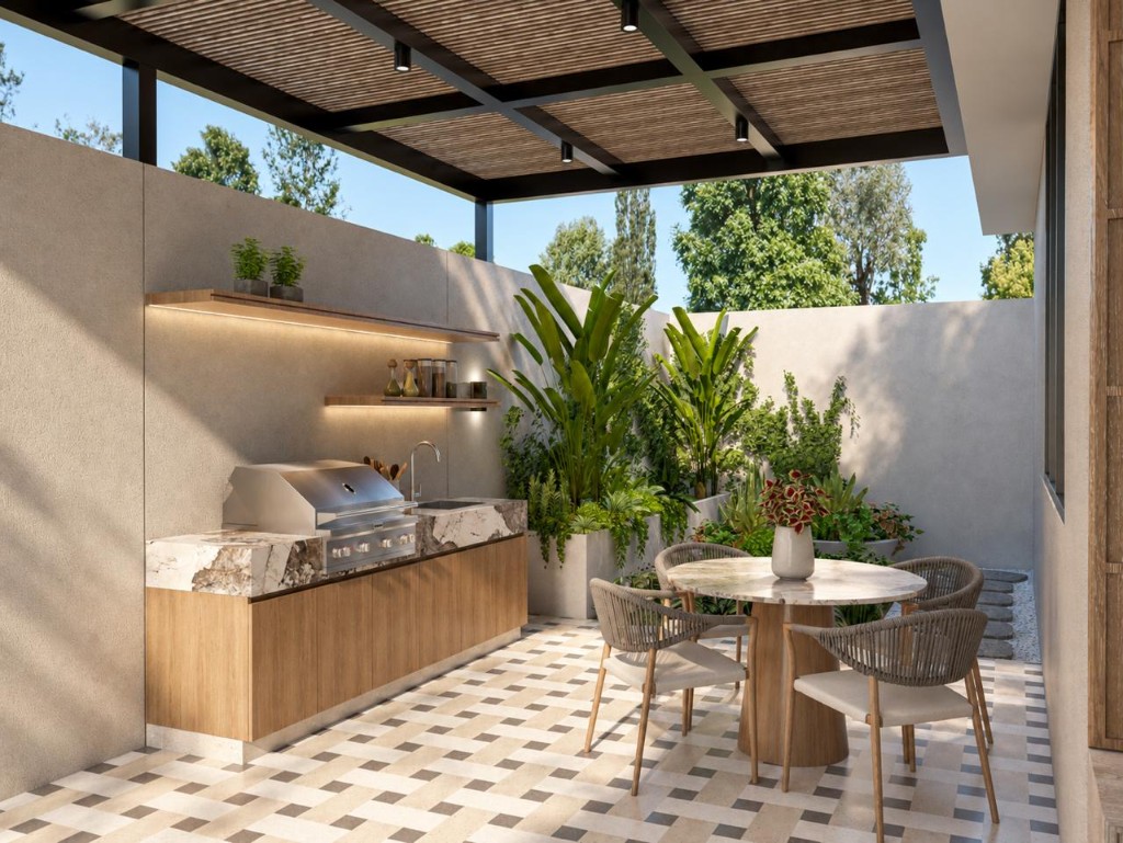 Cocina exterior con parrilla, mesón de mármol y comedor bajo la pérgola